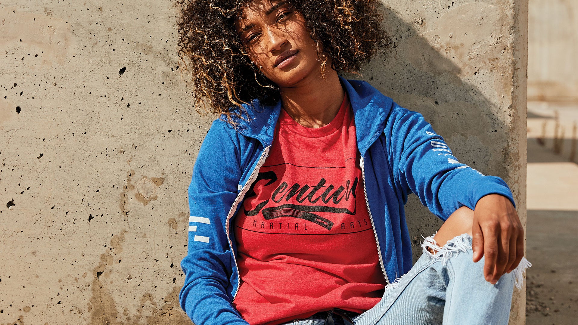 woman sitting against wall wearing apparel from century martial arts